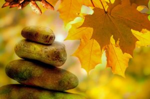 meditation rocks stacked in balance with fall leaves in background photo