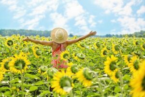 frequencywriter.com ~ March 2021+ Energy Update ~ woman in field of sunflowers feeling freedom